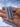 Three pale blue-gray pointed crystal points held in a person's hand against a light blue sky background.